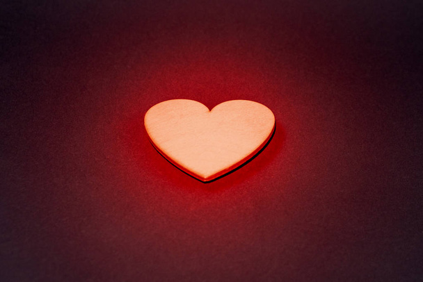 Sparkling golden heart on a dark background. Red backlight, close-up - Foto, Imagen
