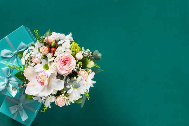 Flower bouquet with gift boxes on green background  copy space flat lay top view - Foto, immagini