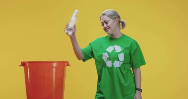 Genç bir kadın plastik şişeyi çöp tenekesine atıyor. - Video, Çekim
