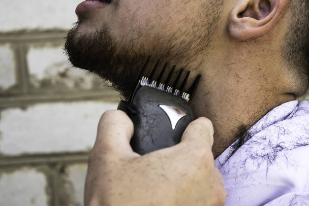el barbero se corta la barba a un tipo con una máquina de esquilar
 - Foto, imagen