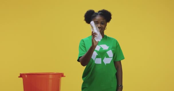 Młoda kobieta rzucając plastikowe butelki do thrash może - Materiał filmowy, wideo