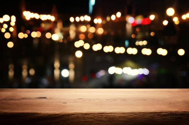 Hintergrund Bild eines Holztisches vor abstrakten verschwommenen Restaurantlichtern - Foto, Bild