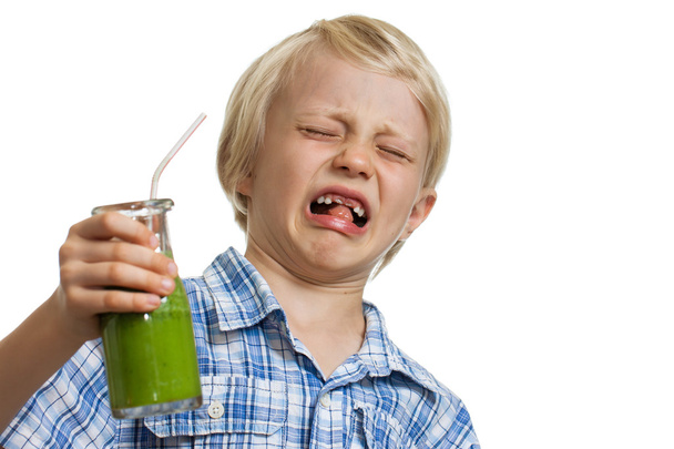 Boy pulling funny face holding green smoothie - Photo, Image