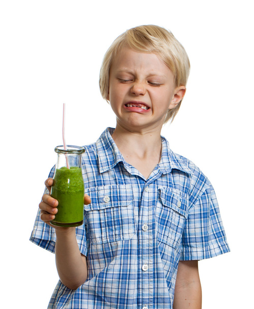 Boy pulling face holding green smoothie - Photo, Image