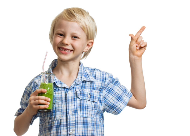 Cute boy holding green smoothie and pointing - 写真・画像