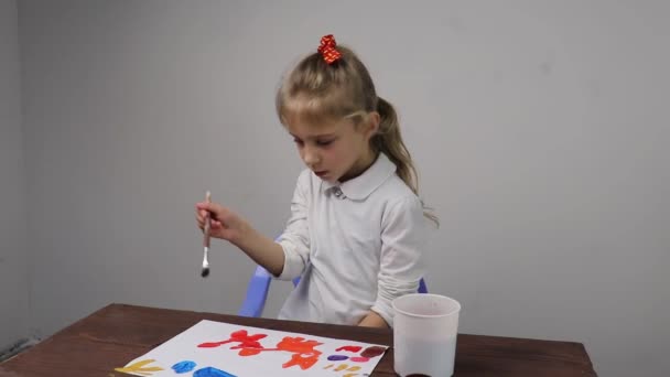 Közelkép. A lány festéket rajzol. Egy üres papírlap. Fogkefe a kézben. - Felvétel, videó