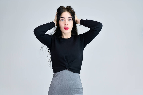 Portrait of a brunette girl with a smile with long hair with excellent makeup in a gray dress on a white background in different poses. Concept of business female photo portrait with emotions. - Fotó, kép