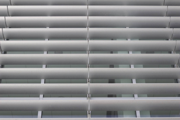 Blick von außen auf energieeffiziente Fensterlamellen an einem hohen Gebäude, die zu seinem attraktiven, modernen Design beitragen - Foto, Bild