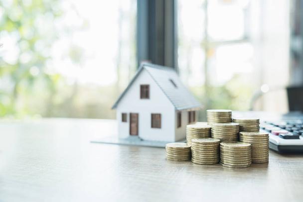 Risparmiare soldi per case e immobili. Stack monete e modello di casa sul tavolo
. - Foto, immagini