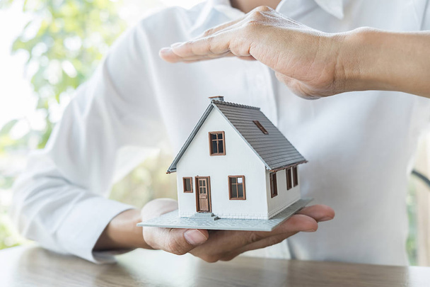 Biztosítási koncepció. Ügynök kéz védelme ház modell, amely azt mutatja, hogy az ügyfelek, hogy a ház biztosítás. - Fotó, kép