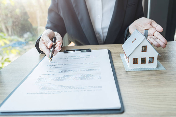 Агент по недвижимости и клиент подписывает договор на покупку дома, страховой или кредитной недвижимости. - Фото, изображение