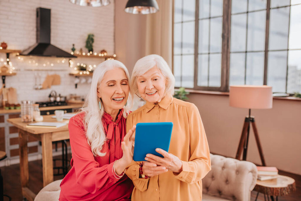 Two pleasant-looking elderly grey-haired women watching video - Photo, Image