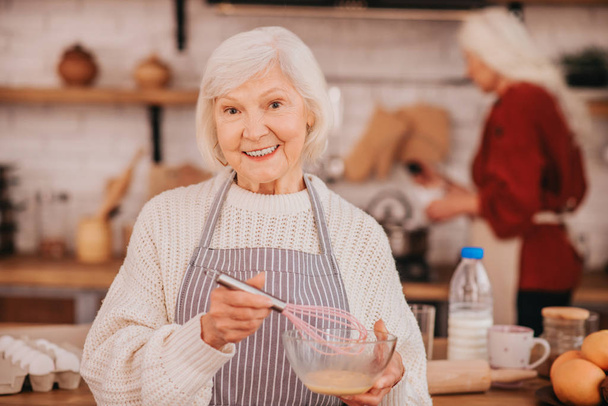 Grey-haired smiling lady in apron looking positive - Фото, изображение