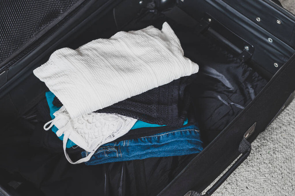 packing for a holiday concept, luggage with pile of clothes insi - Фото, изображение