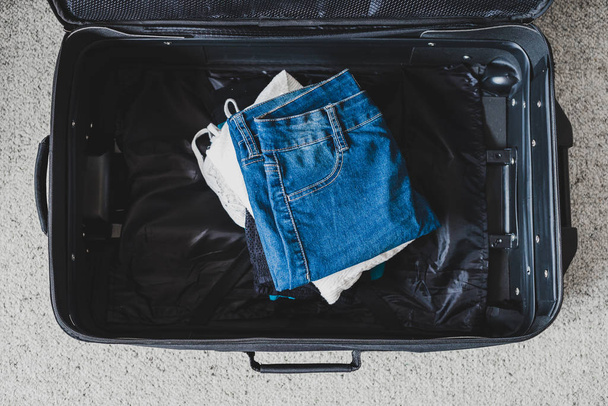 packing for a holiday concept, luggage with pile of clothes insi - Фото, зображення