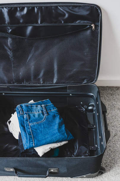 packing for a holiday concept, luggage with pile of clothes insi - 写真・画像