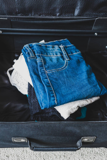 packing for a holiday concept, luggage with pile of clothes insi - Фото, изображение