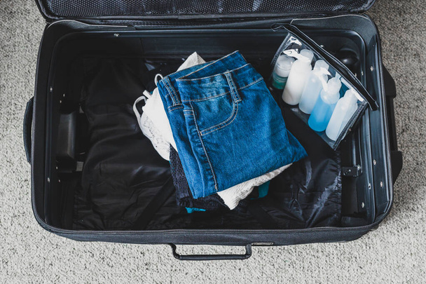 packing light for a holiday concept, luggage with pile of clothe - Foto, imagen