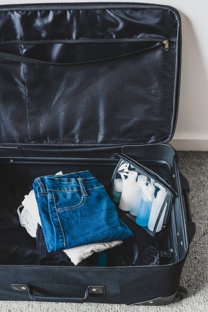 packing light for a holiday concept, luggage with pile of clothe - 写真・画像