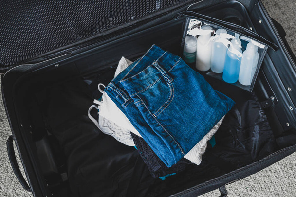 packing light for a holiday concept, luggage with pile of clothe - Foto, Bild