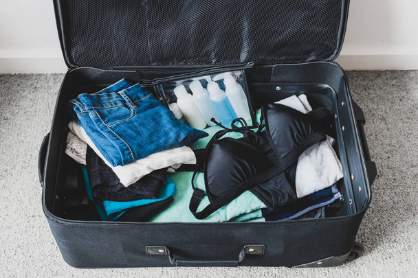 packing for a holiday concept, luggage with pile of clothes beac - 写真・画像