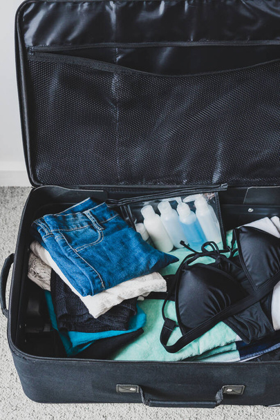 packing for a holiday concept, luggage with pile of clothes beac - Foto, immagini