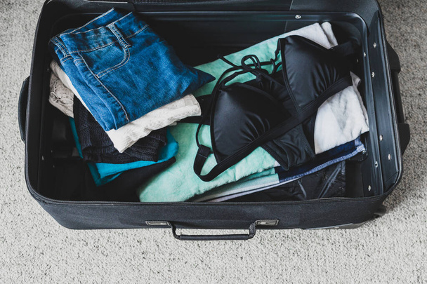 packing for a holiday concept, luggage with pile of clothes beac - Foto, Imagem