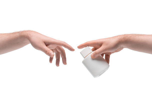 Two male hands passing one another small white bottle on white background - Fotoğraf, Görsel