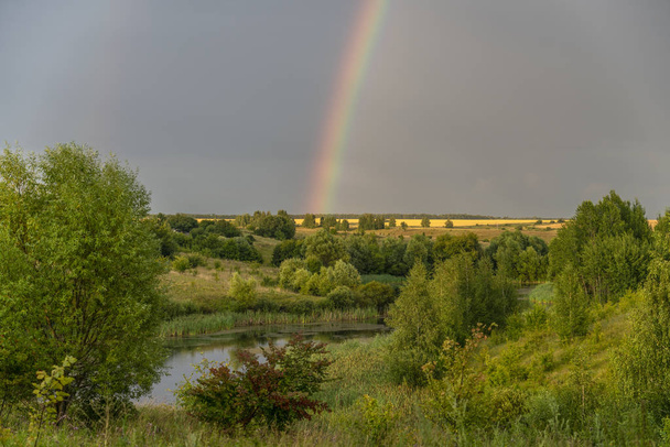 bright rainbow over the pond, ravine and tree planting - Zdjęcie, obraz