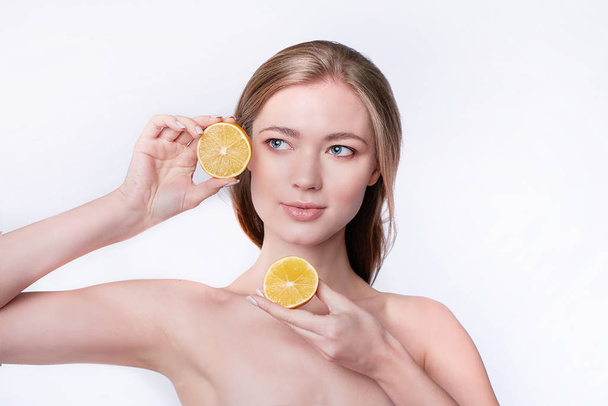 portrét krásné mladé ženy držící plátky pomeranče, péče o obličej - Fotografie, Obrázek