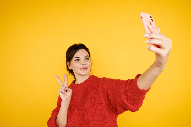 Potrait of woman taking self photo and showing peace sign isolated. - Foto, Imagem
