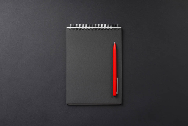 notatnik z czerwonym piórem na czarnym tle - Zdjęcie, obraz