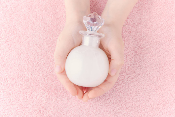 felső nézet kezek egy üveg folyékony szappan vagy fürdőkád hab pasztell rózsaszín háttér - Fotó, kép