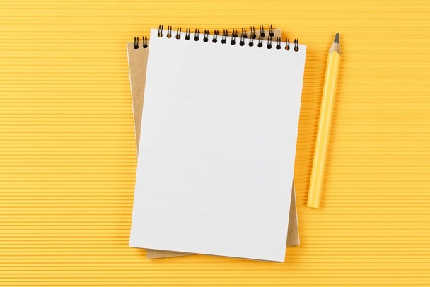 cuaderno con lápiz sobre papel amarillo corrugado
 - Foto, Imagen