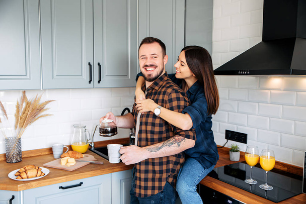 Loving couple in a stylish gray kitchen - Foto, afbeelding