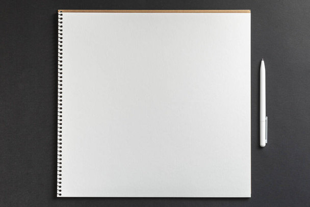 ноутбук с белой ручкой на черном фоне - Фото, изображение