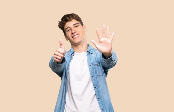 Jóképű fiatalember számolva hat ujjal elszigetelt háttér - Fotó, kép