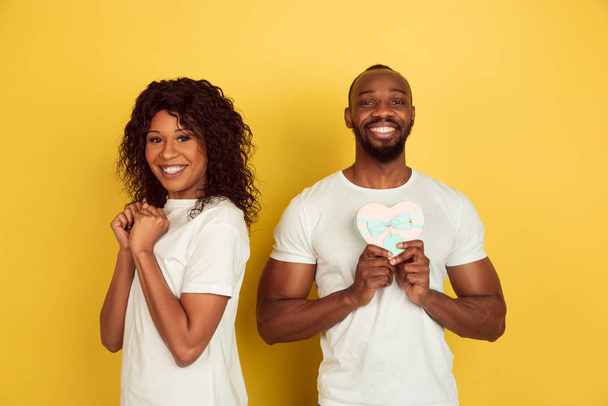 Valentines day celebration, happy african-american couple isolated on yellow background - Φωτογραφία, εικόνα