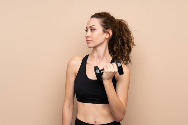 Young sport woman over isolated background making weightlifting with kettlebell - Photo, image