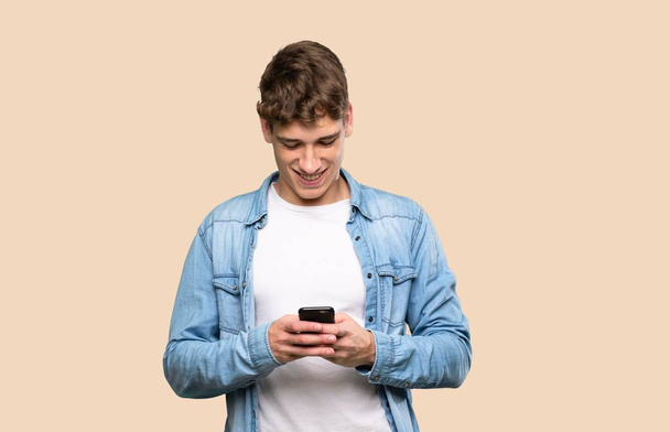 schöner junger Mann sendet eine Nachricht mit dem Handy über isolierten Hintergrund - Foto, Bild