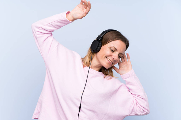 Жінка слухає музику над ізольованою синьою стіною
 - Фото, зображення