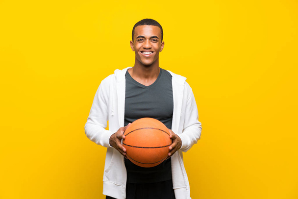 Αφροαμερικανός παίχτης του μπάσκετ πάνω από απομονωμένο κίτρινο φόντο - Φωτογραφία, εικόνα