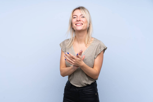 junge blonde Frau über isoliertem blauem Hintergrund applaudiert - Foto, Bild
