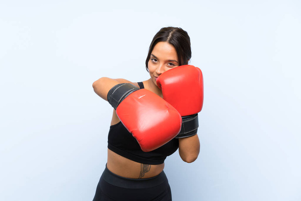 Giovane ragazza sportiva con guanti da boxe su sfondo blu isolato
 - Foto, immagini