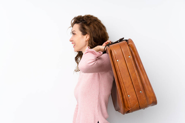 Молодая красивая женщина на изолированном фоне держит винтажный портфель
 - Фото, изображение