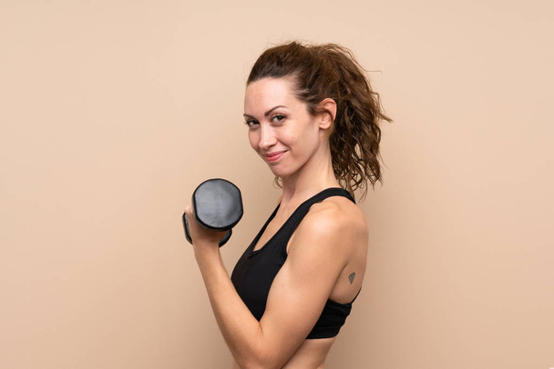 Young sport woman over isolated background making weightlifting - Photo, Image
