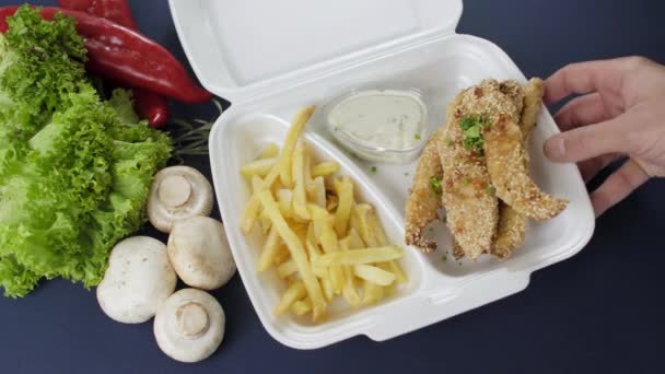 Packing takeaway food in styrofoam box. Fresh delivery pack meal with chicken nuggets and french fries  - Footage, Video