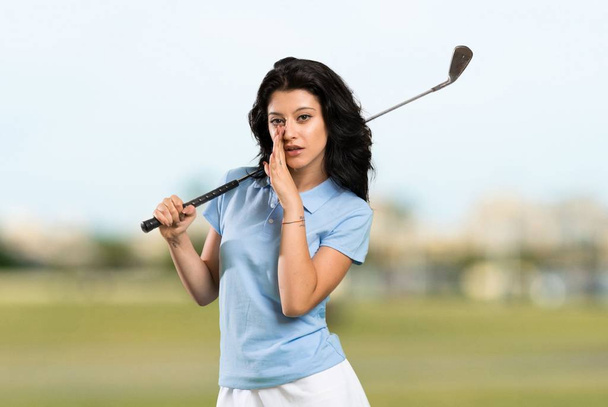 Fiatal golfozó nő suttog valamit a szabadban. - Fotó, kép