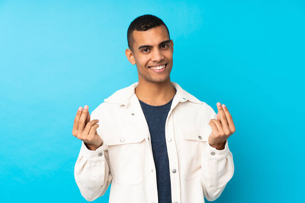 Young African American man over isolated blue background making money gesture - Foto, imagen