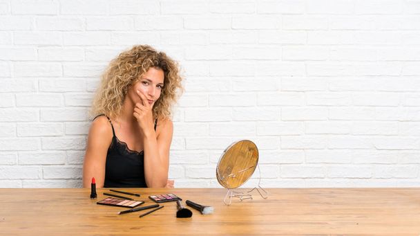 Mladá žena se spoustou make-upu v tabulce, která uvažuje o myšlence - Fotografie, Obrázek
